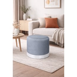 Nowoczesna pufa LUX IMO w pastelowym błękicie z białą podstawą, ustawiona w jasnym salonie na dywanie; za nią sofa z pomarańczow